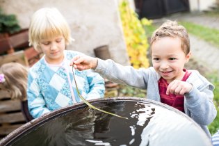 Zatímco dospělí klábosí uvnitř, děti se sešly venku u sudu